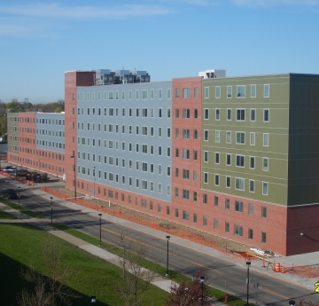 An aerial view of the Student Apartment Complex at Buffalo State University, featuring a long, multi-sectioned building with varied colored panels and brick accents, taken on July 21, 2009